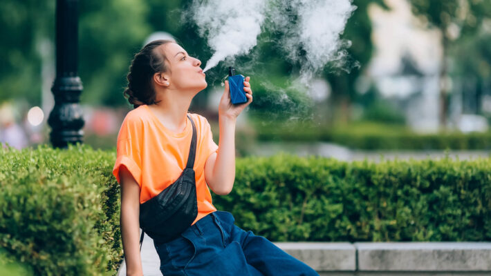 Junge Frau raucht E-Shisha aus Automat